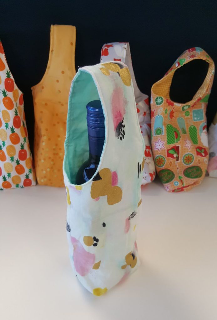 Close up of one wine bag with a bottle of red wine inside it set against a backdrop of other wine bags