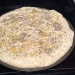 Dough stretched out on 12" pizza plate with rosemary, crushed garlic, olive oil, kosher salt and cracked black pepper