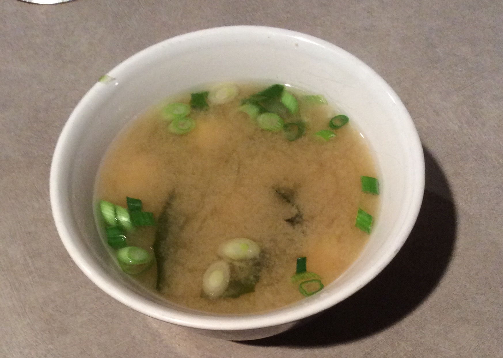 Bowl of miso soup with fresh green onions added after cooking