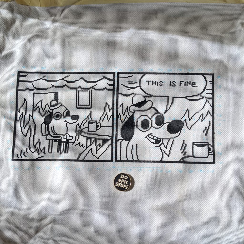 Both panels of the This is fine meme done, in black outline cross-stitches
