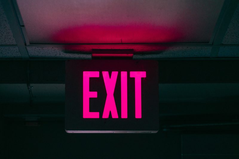 Dark background with luminous pink EXIT sign showing in the center